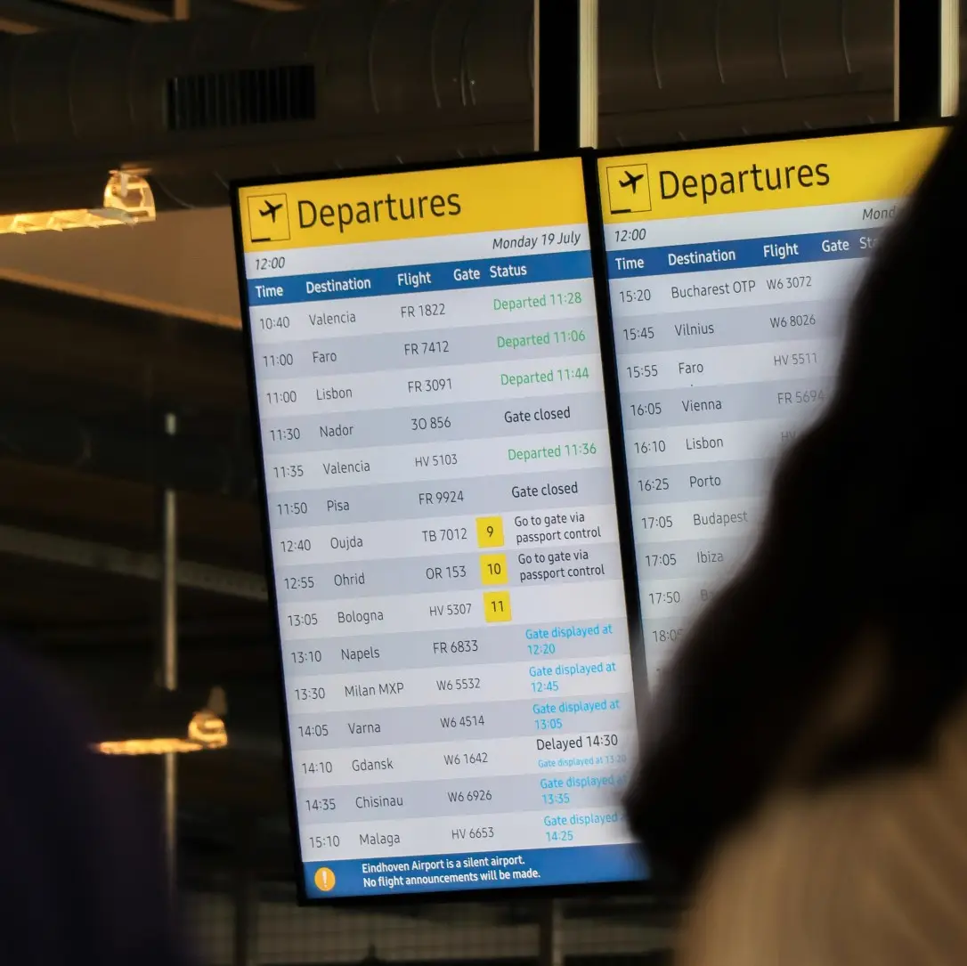 Airport digital signage screens showing flight departure information