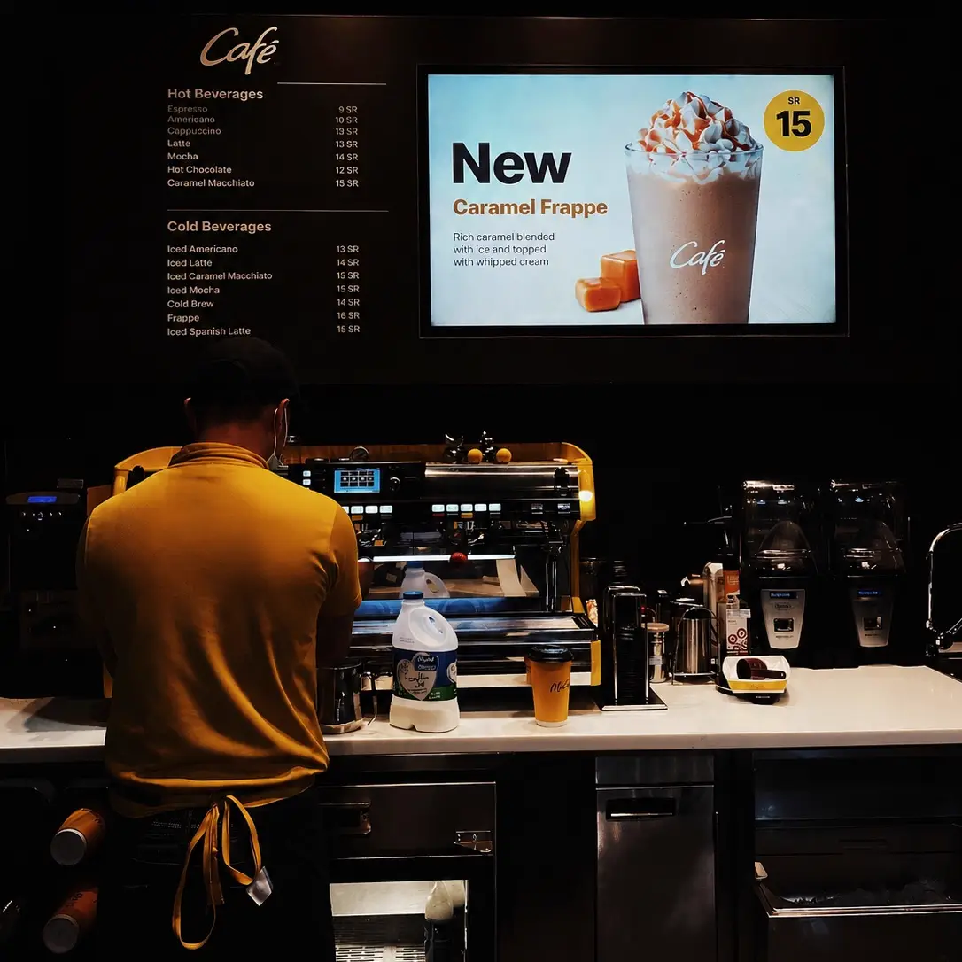 Café digital signage screen displaying a caramel frappe promotion and menu prices