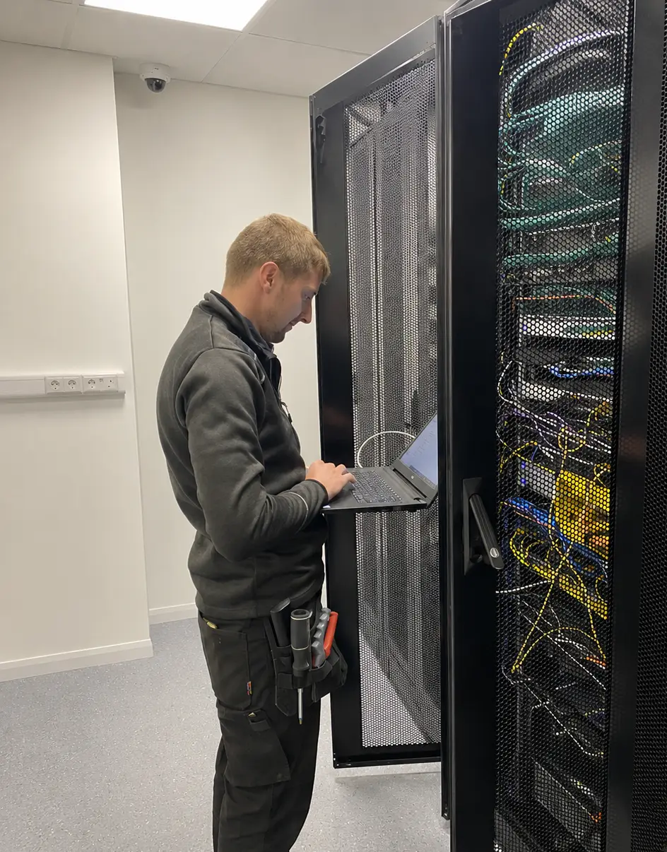 Zintek technician working on a laptop beside server racks in a data centre.